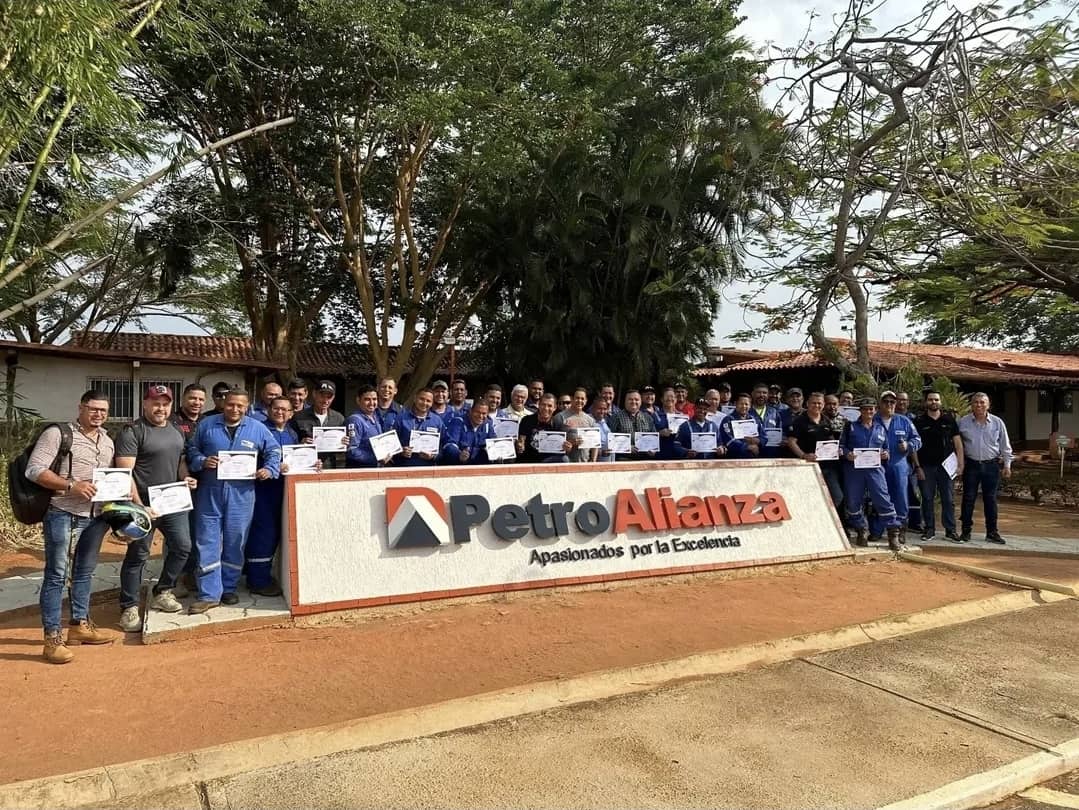 Equipo de PetroAlianza reunido con certificados frente al emblema corporativo